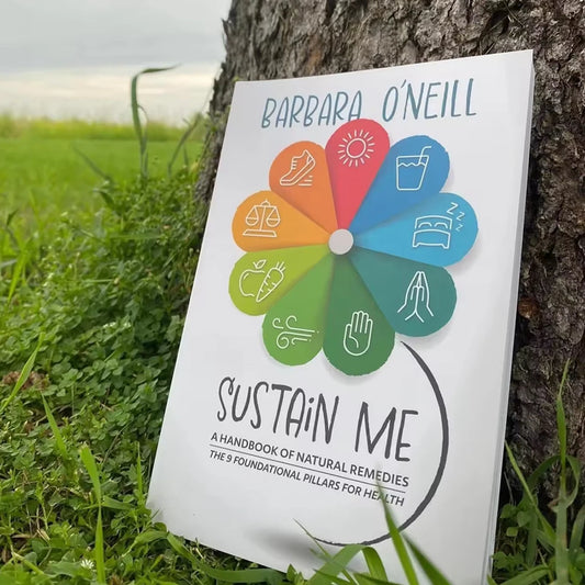 Book titled 'Sustain Me' by Barbara O'Neill leaning against a tree on grass